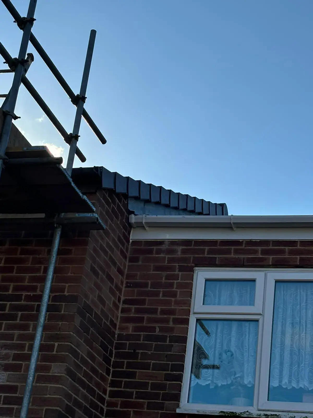 A brick building with a weather vane on top of it.