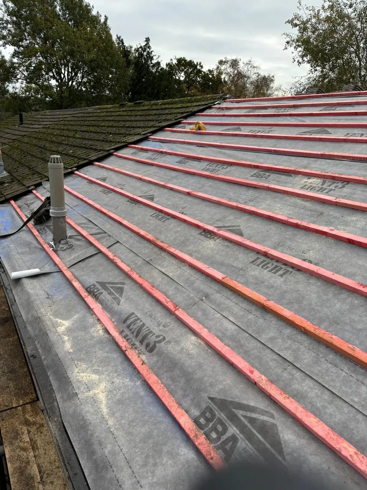 A roof with a metal pipe sticking out of it.
