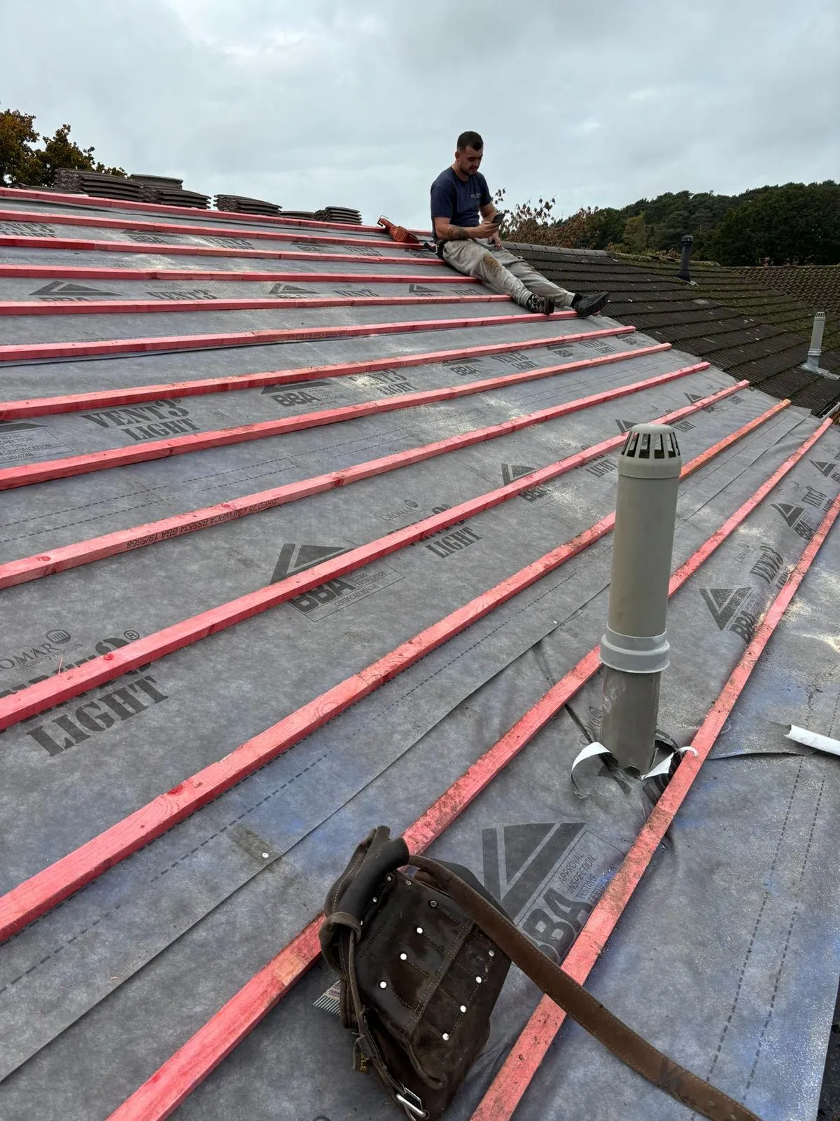 A man is sitting on the roof of a house.