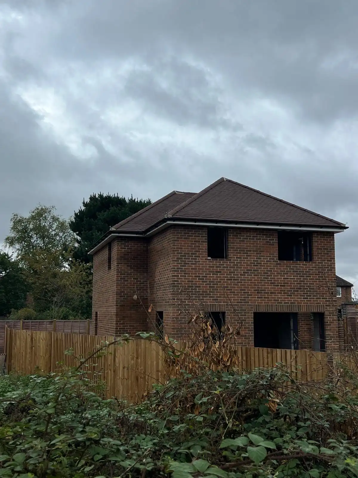 brick house with a brown roof and a fence